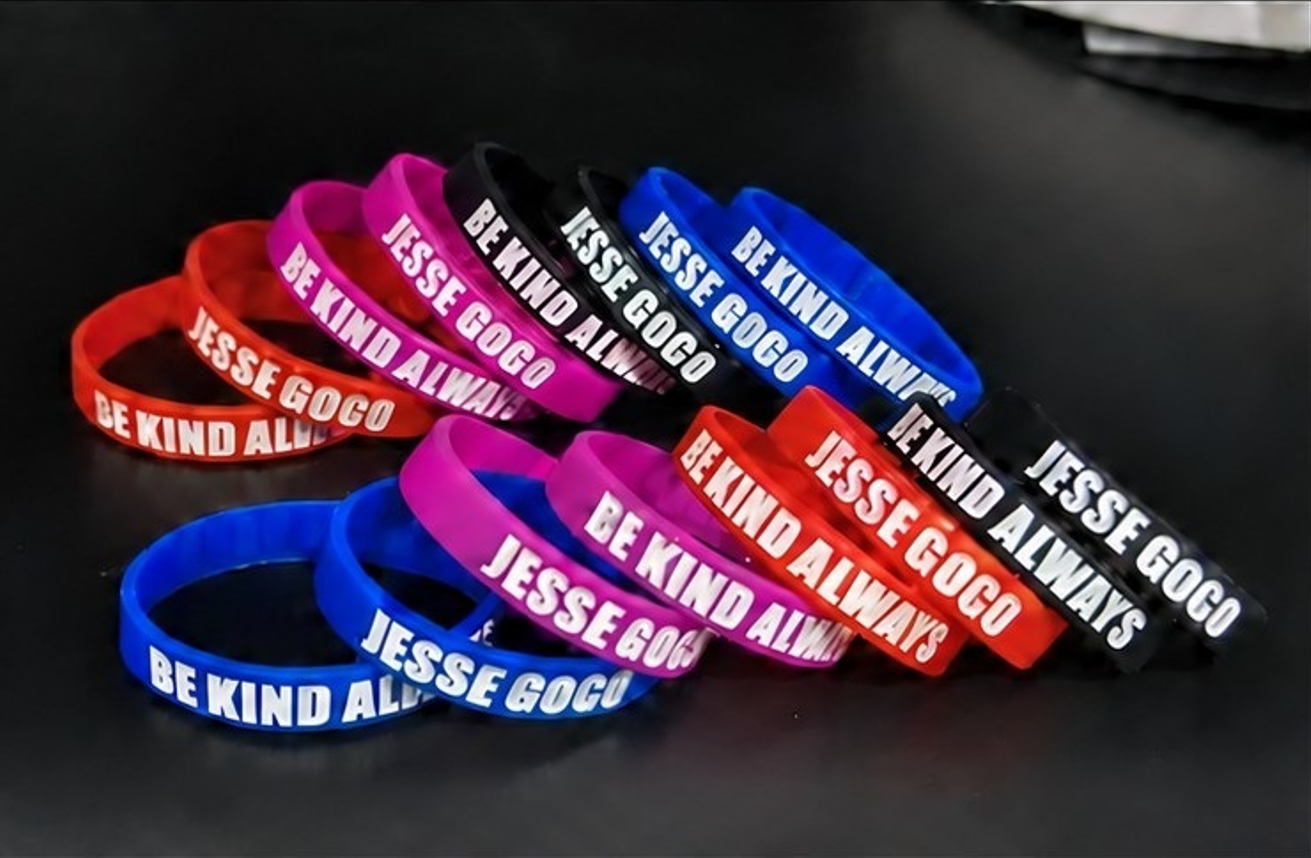 Be Kind Always and Jesse Gogo wristbands in red, pink, black, and blue.