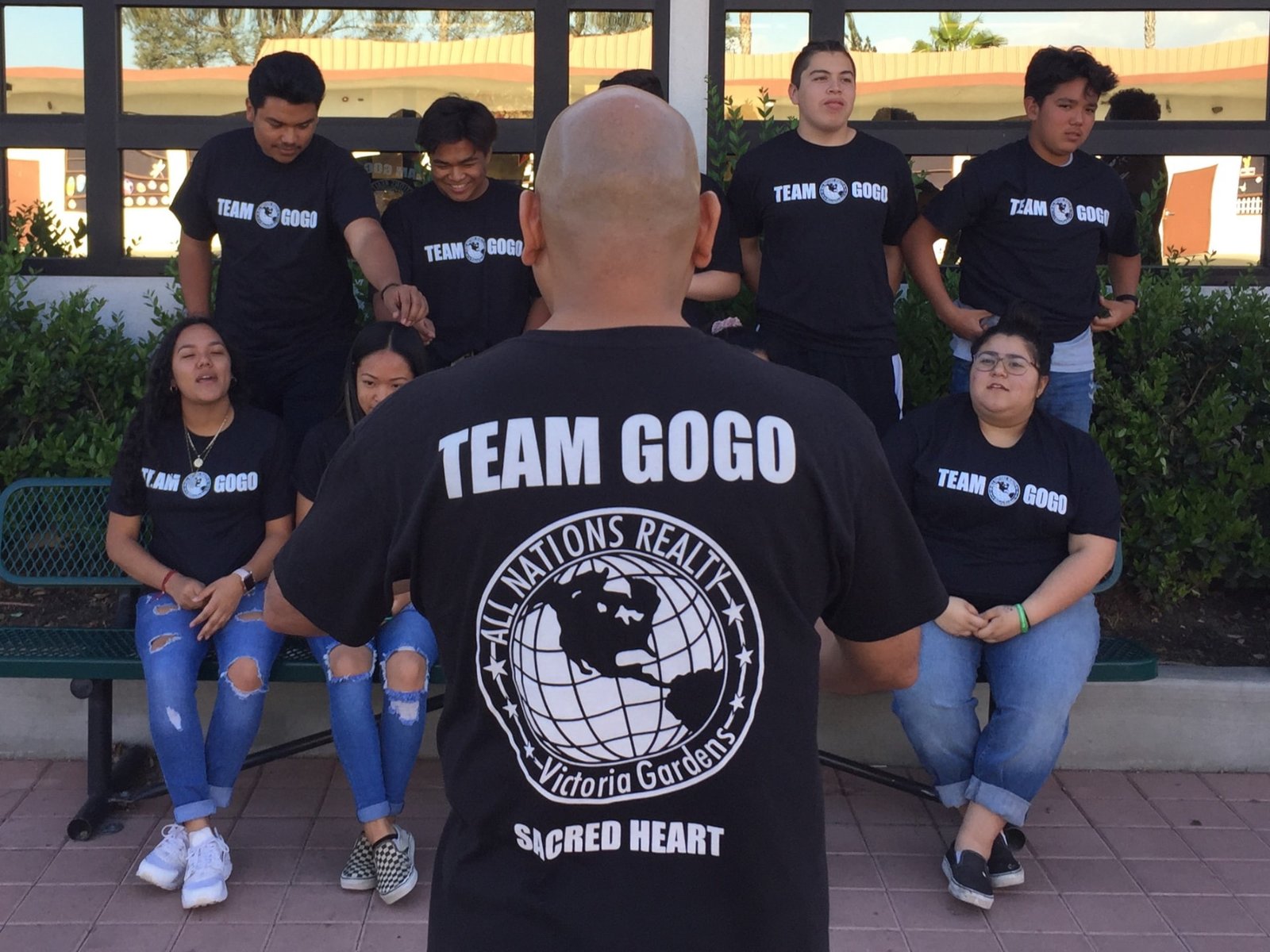 Jesse Gogo, seen from behind in a TEAM GOGO Sacred Heart shirt, facing his Confirmation group.